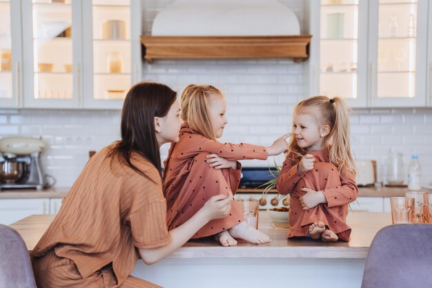 Zusters in pyjama spelen op de keuken Twee kleine blonde zusjes lachend zit op de keukentafel