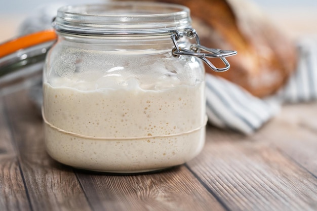 Zuurdesemstarter voeren in een glazen glazen pot voor het bakken van ambachtelijk brood.