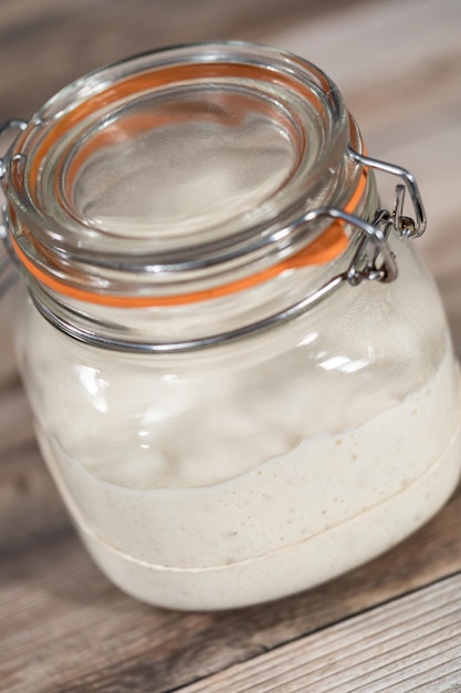 Zuurdesemstarter voeren in een glazen glazen pot voor het bakken van ambachtelijk brood