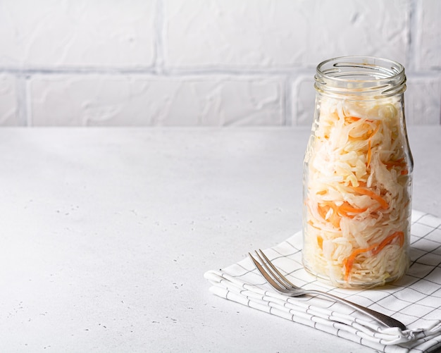 Zuurkool in een glazen pot. Gefermenteerde groenten op een lichte achtergrond