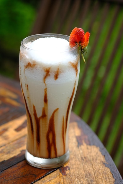 zuurzaksap in een helder glas. gesmolten chocolade. vers drankje van tropisch fruit. houten tafel.