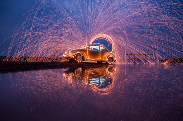 Zwaai staalwolvuur op een auto en zeewaterreflectie