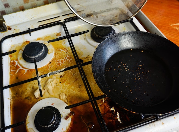 Zwaar vervuild gasfornuis en koekenpan in de keuken