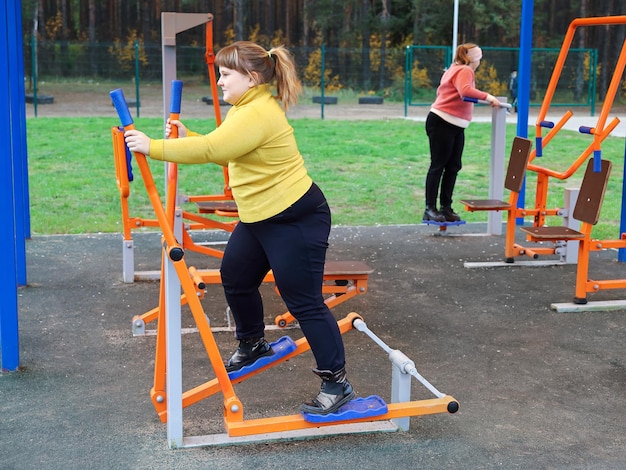 Zwaarlijvig meisje doet buiten sportoefeningen op straatsimulators