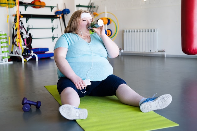 Zwaarlijvige vrouw drinkwater na training