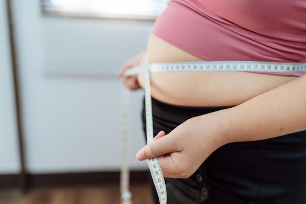 Zwaarlijvige vrouw met dik overstuur over haar buik Vrouw met overgewicht raakt zijn dikke buik aan en wil afvallen Dikke vrouw maakt zich zorgen over gewicht dieet levensstijl