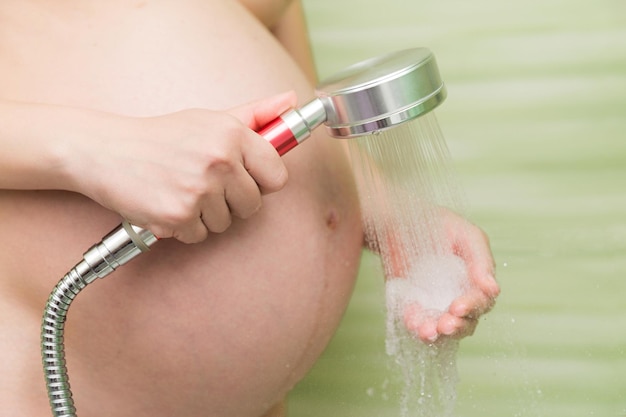 Zwanger meisje controleert de temperatuur van de douche voor het baden