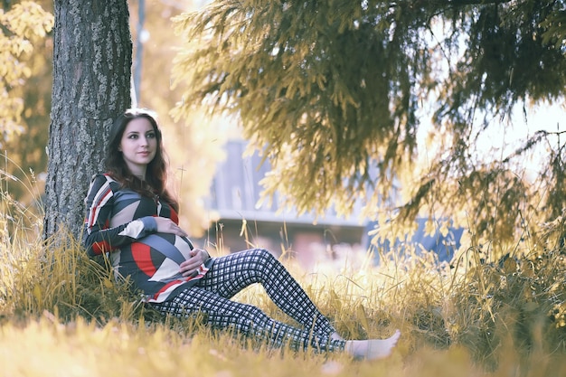 Zwanger meisje in een jurk in de natuur op een wandeling