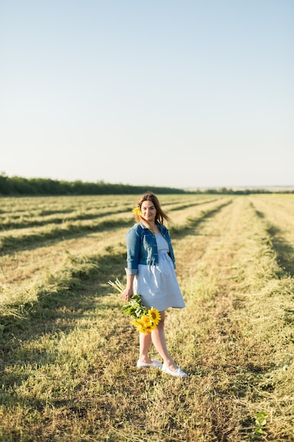 Zwanger meisje in zonnebloemen, gelukkig meisje dat op de baby wacht