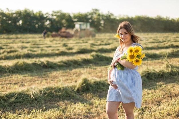 Zwanger meisje in zonnebloemen, gelukkig meisje dat op de baby wacht