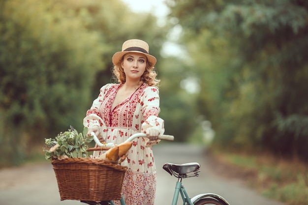 Zwanger meisje retro Franse stijl met fiets op een bosweg