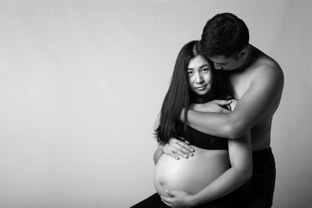 Zwanger paar die buik samen met witte achtergrond houden.