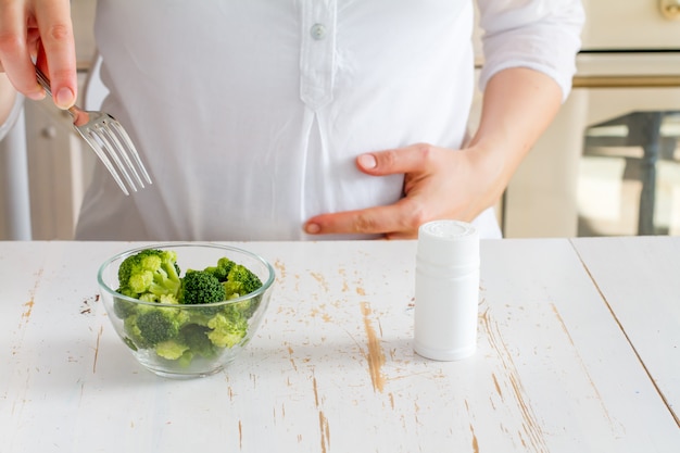 Zwanger wijfje dat broccoli over vitaminen kiest