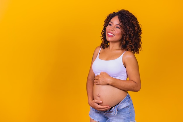 Zwangere afrovrouw op gele achtergrond