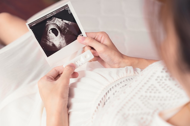 Zwangere Aziatische vrouw die echoscopie bekijkt