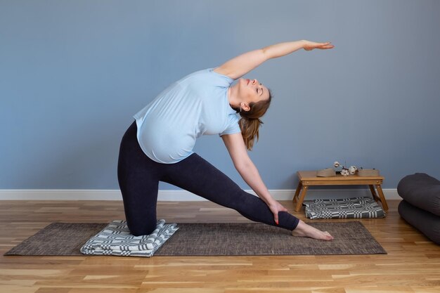Zwangere blanke vrouw die in yoga asana staat