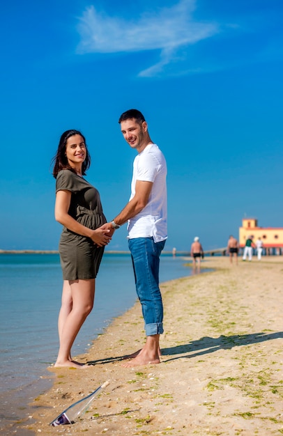Zwangere gelukkige paar op strand