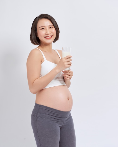 Zwangere jonge Aziatische vrouw met een glas in hand melk.