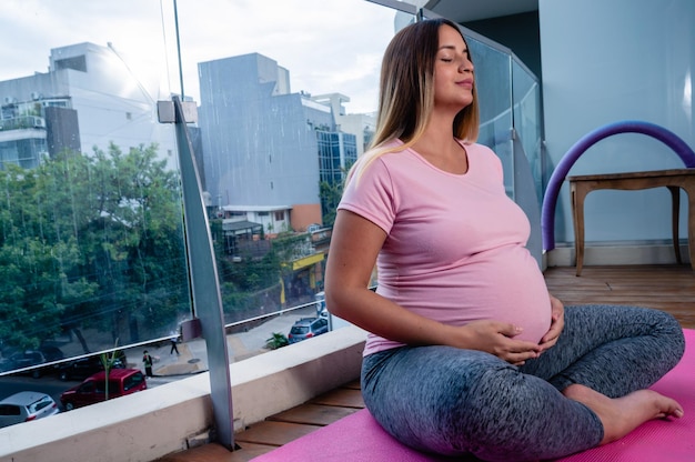 Zwangere jonge vrouw die mediteert en yoga beoefent