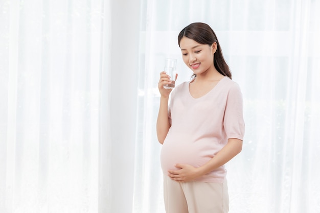 Zwangere jonge vrouw met een glas water
