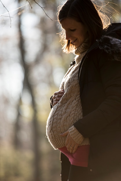 Foto zwangere jonge vrouw met handen op buik