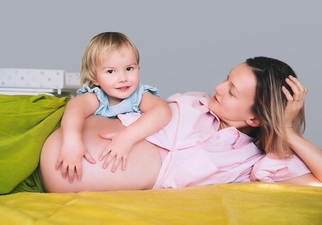 zwangere moeder en dochter samen thuis vrouw met haar eerste kind tijdens tweede zwangerschap