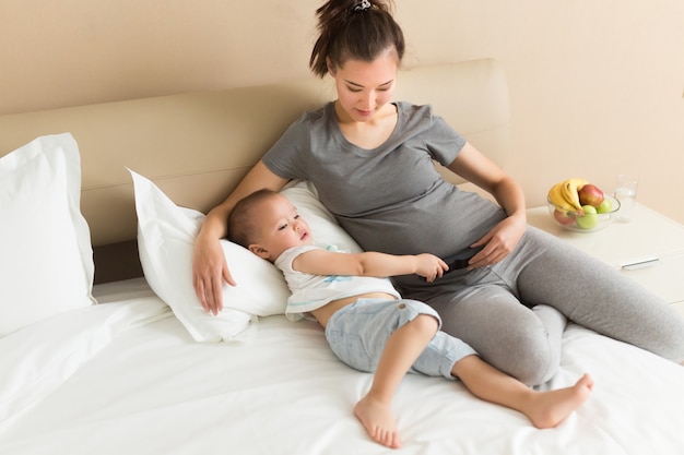 Zwangere moeder en haar zoontje brengen tijd samen thuis door in bed