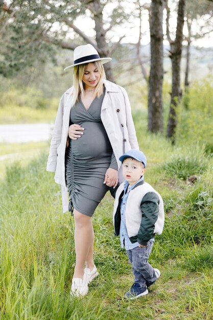Zwangere moeder en haar zoontje wandelen in het bos en brengen samen tijd door