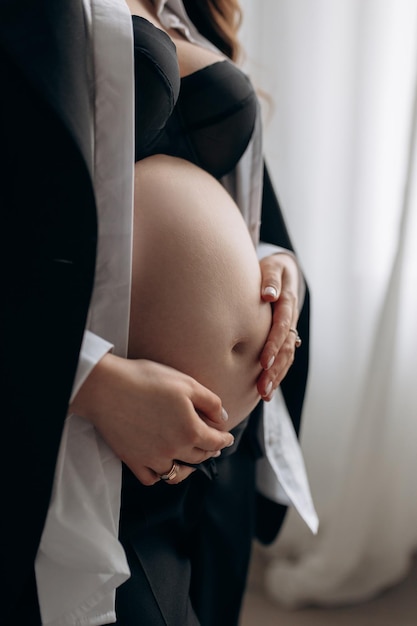Zwangere moeder met een mooie buik in een zwart top wit shirt en jas Stylish zwangerschap