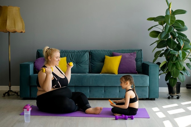 Zwangere moeder met obesitas gaat sporten met dochter die moeder morele steun geeft