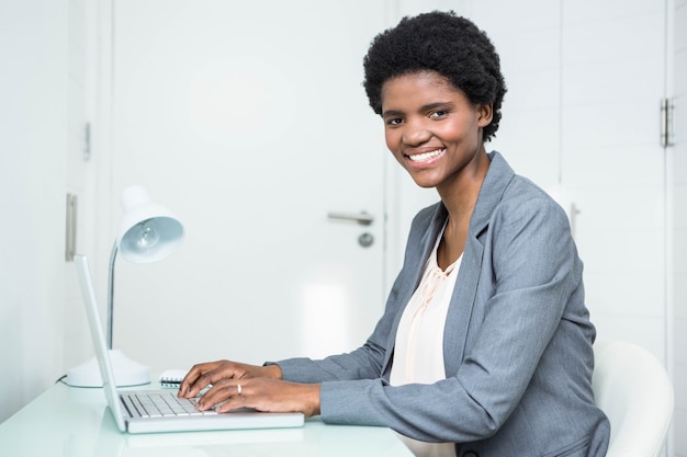 Zwangere onderneemster die laptop in het bureau met behulp van