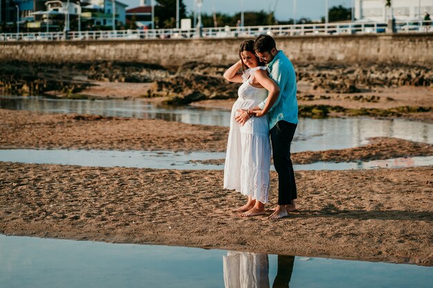 Zwangere paar fotograferen op het strand bij zonsondergang