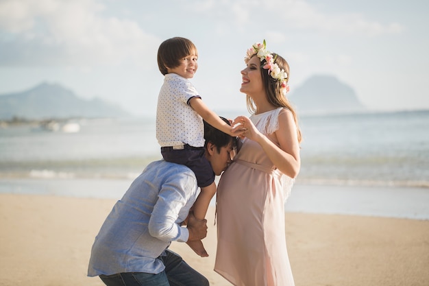 Zwangere vrouw, baby en gemengd ras man op het strand