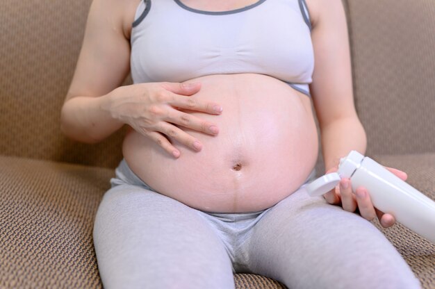 Zwangere vrouw blijft alleen thuis. Zwangerschap op zoek naar een nieuwe baby die eraan komt.