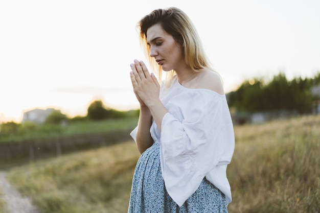 Zwangere vrouw buiten bidden bij zonsondergang. Concept voor geloof, spiritualiteit en religie. Vrede, hoop