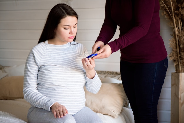 Zwangere vrouw controleert de bloedsuikerspiegel, diabetestest.