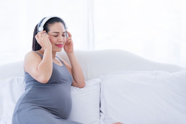 Zwangere vrouw die aan muziek op het bed luistert. geestelijke gezondheidszorg en zwangerschap.