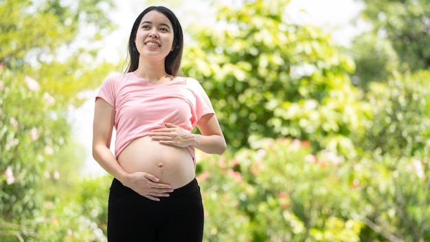 Zwangere vrouw die buik aanraakt in het stadspark Zwanger Ontspannen en sporten Mooie tedere stemmingsfoto van zwangerschap
