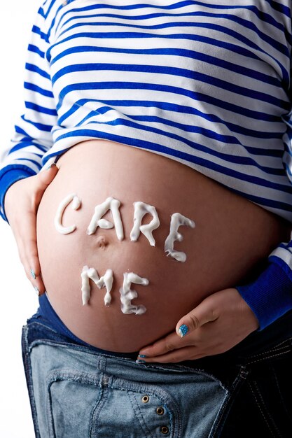 Zwangere vrouw die 'care me'-woord op haar buik schrijft. Isoleren.