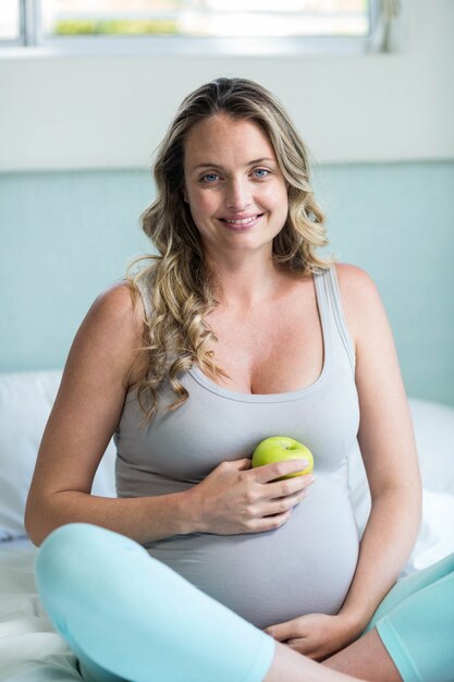 Zwangere vrouw die een appel in haar slaapkamer houdt