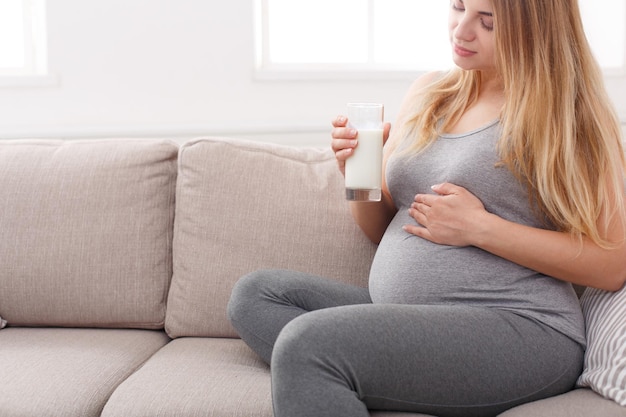 Zwangere vrouw die een glas melk kopieert. Jonge aanstaande blonde genieten van gezonde drank. Gezondheidszorg, voeding, vitamines, zwangerschapsconcept