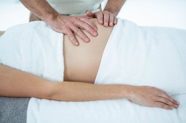 Zwangere vrouw die een maagmassage van masseur ontvangt in health spa