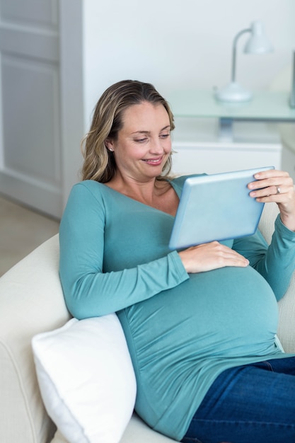 Zwangere vrouw die een tabletcomputer op de laag met behulp van