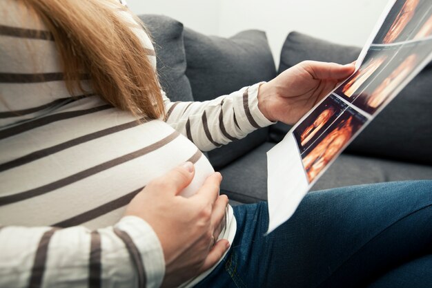 Zwangere vrouw die haar echografie bekijkt