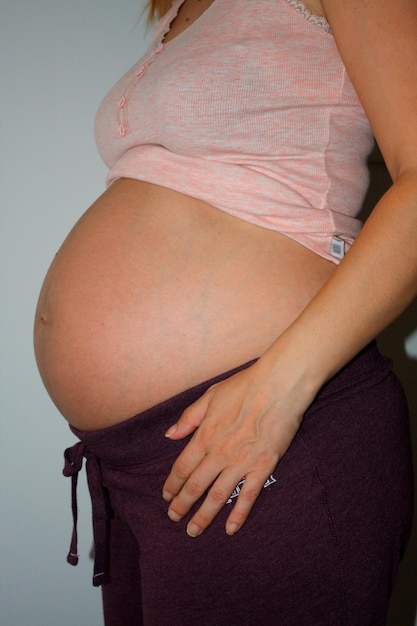 Zwangere vrouw die haar grote buik aanraakt Close-up