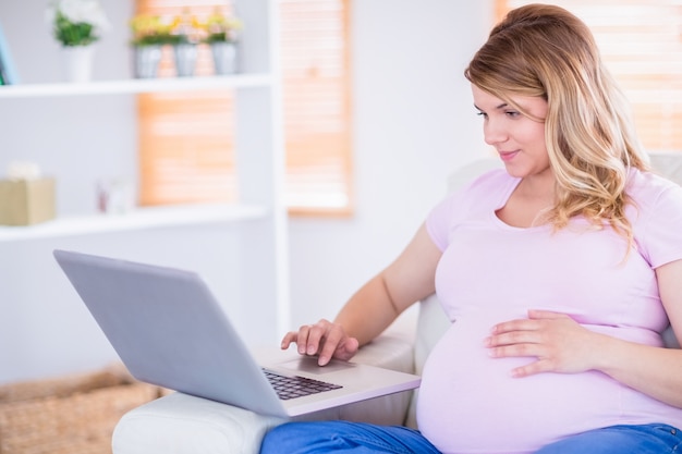 Zwangere vrouw die haar laptop met behulp van