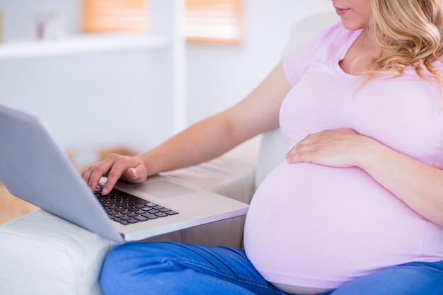 Zwangere vrouw die haar laptop met behulp van