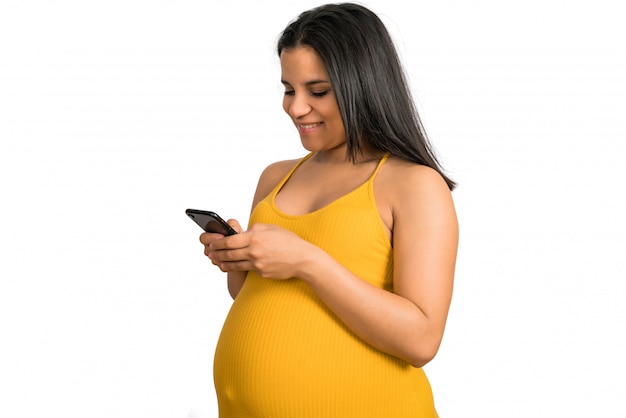 Zwangere vrouw die haar mobiele telefoon met behulp van.