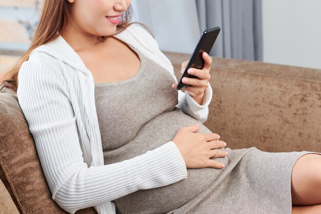 Zwangere vrouw die haar telefoon controleert