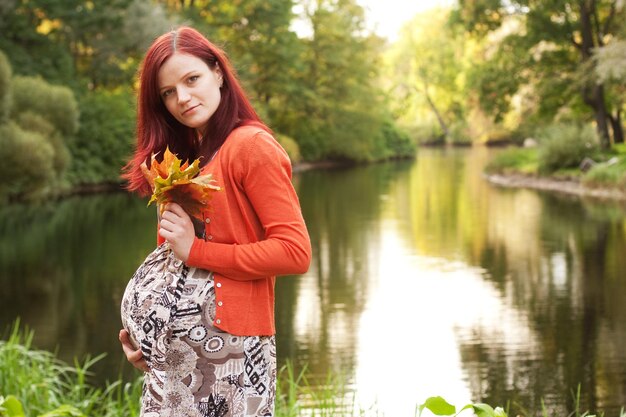 Zwangere vrouw die in de herfstpark loopt